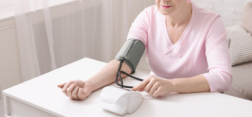 Mature woman checking her blood pressure with tonometer