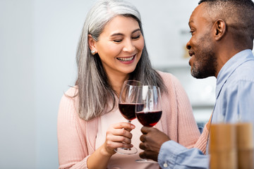selective focus of smiling multicultural friends  clinking with wine glasses
