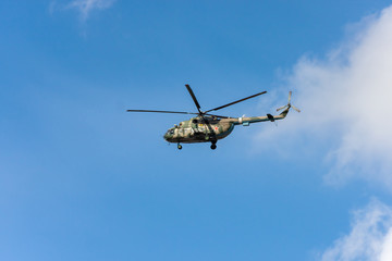 Fototapeta na wymiar The military helicopter against the blue sky.