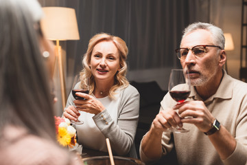 selective focus of smiling woman and man talking with friend during dinner