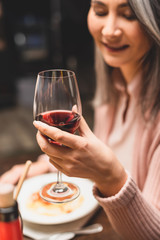 selective focus of smiling asian woman holding wine glass during dinner