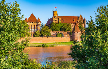 Obraz premium Panoramic view of the defense walls and towers of the Medieval Teutonic Order Castle in Malbork, Poland from across the Nogat river