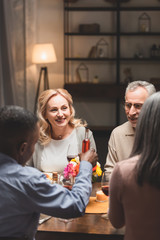 selective focus of smiling man and woman talking with multicultural friends during dinner