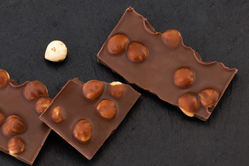 milk chocolate pieces with nuts on a dark background
