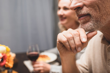 cropped view of man and smiling woman on background during dinner