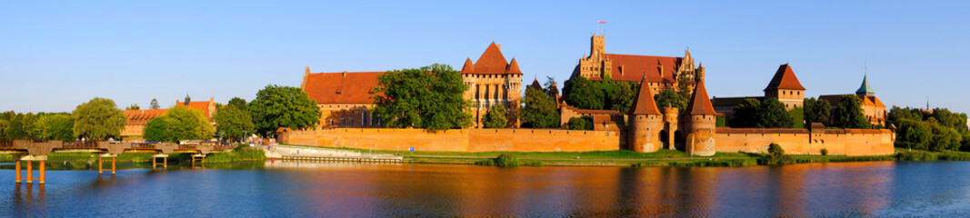 Fototapeta na wymiar Panoramic view of the defense walls and towers of the Medieval Teutonic Order Castle in Malbork, Poland from across the Nogat river
