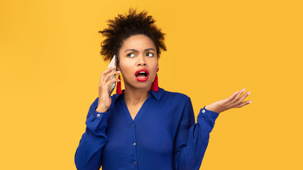 Upset young afro woman talking on mobile phone