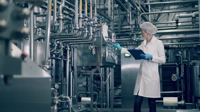 Lady inspector is recording info from a factory machine