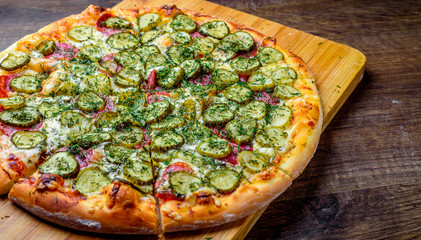 Pizza with Mozzarella cheese, salami, bacon, Tomato sauce, fresh dill, Spices and pickled cucumbers. big dill pizza on wooden table background