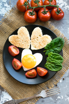 Vertical photo.Romantic breakfast for Valentine's day. Fried eggs and bread tosts heart shape. 14 February