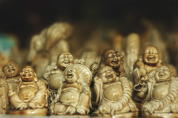 Statues of laughing Chinese gods Are on the counter with Souvenirs. The concept of meditation, luck, happiness, travel, health, money wealth.