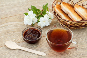 Glass cup of tea, bread, strawberries with white jasmine flowers