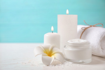 Composition with cream and burning candles on white wooden table. Spa treatment