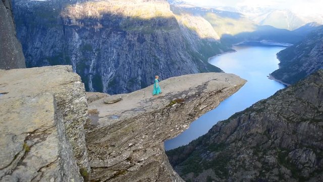 Girl in the beautiful dress on the edge of cliff on Trolltung, Norway. Slow motion video.