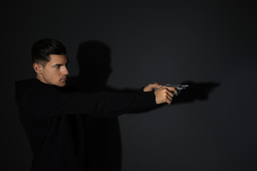 Professional killer with gun on black background