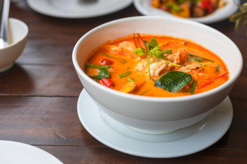Tom Yam kung Spicy Thai soup with shrimp in white bowl on wood table. With copy space for text or design.