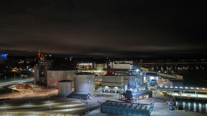 Fototapeta na wymiar Modern grain terminal at night. Metal tanks of elevator. Grain-drying complex construction. Commercial grain or seed silos at seaport. Steel storage for agricultural harvest.