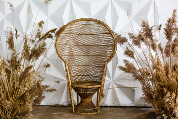 Peacock wicker chair in a spacious bedroom interior. Rattan peacock armchair by the white empty...