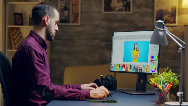 Photographer looking closely to computer while retouching photos