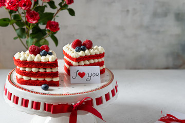 Red velvet cakes with raspberries, blueberries and whipped cream in heart shape on gray background....