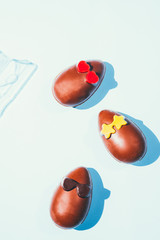 Funny chocolate eggs glasses, eaaster image with chocolate small eggs on a blue board, top view, flatlay with had directional light with deep shadows