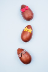 Funny chocolate eggs glasses, eaaster image with chocolate small eggs on a blue board, top view, flatlay