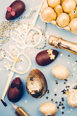 Easter party theme image, conceptual image, golden egg. champagne, golden items with party  glasses, on a blue background, top view, retro tonality