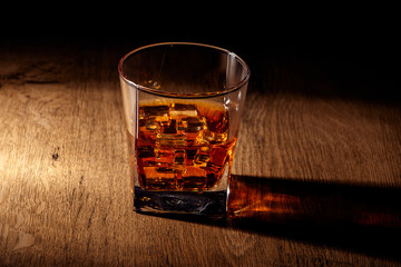 Whiskey with ice or brandy in a glass on a rustic background. Whiskey with ice in a glass. Whiskey or brandy. Selective focus.