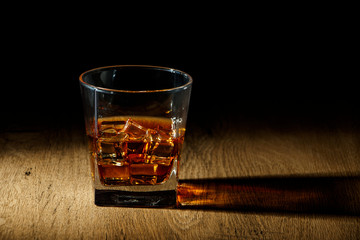 Whiskey with ice or brandy in a glass on a rustic background. Whiskey with ice in a glass. Whiskey...