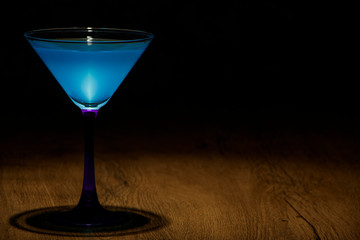 Blue cocktail in a glass for martini on a gray background. Blue cocktail with martini on a gray stone background.