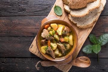 Irish dinner. Beef meat stewed with potatoes, carrots and soda bread on wooden background, top...