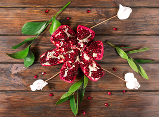 open pomegranate and flowers on a wooden background