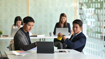 Photo of board of directors discussing about them business by using tablet at the modern meeting room over employee as background.