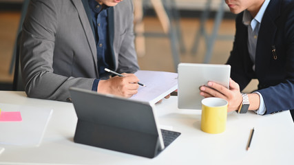 Cropped shot of smart business team discussing with tablet and document at the meeting desk.