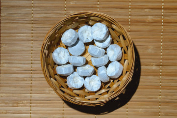 puer tea wrapped in white paper lies in a wicker basket. on a wooden background.