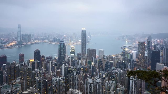 4k time lapse of hazy and misty day to night sunset scene at Hong Kong, aerial view. Zoom out