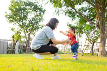 Baby learning to walk first steps with mother help at the park.The concept of baby development learning to walking..