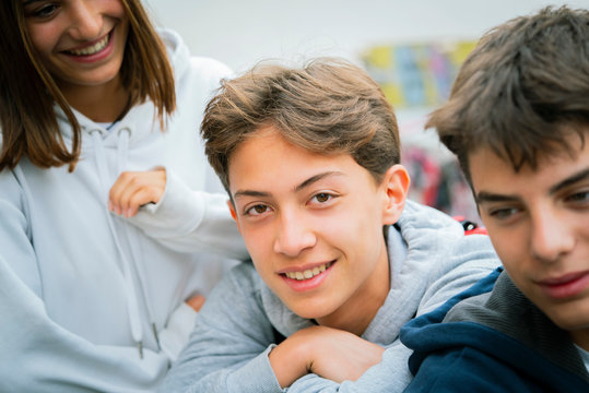 Close-up of smiling teenage friends sitting outdoors