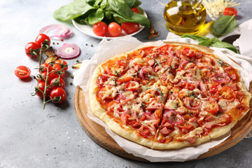 Italian cuisine. Pizza on a white and gray background. Cooking process. Fresh vegetables and basil. background image, copy space, pizza with hands.