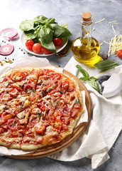 Italian cuisine. Pizza on a white and gray background. Cooking process. Fresh vegetables and basil. background image, copy space, pizza with hands.