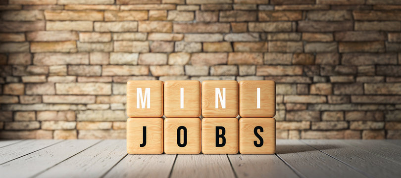 cubes with text "MINI-JOBS" in front of a brick wall on wooden floor