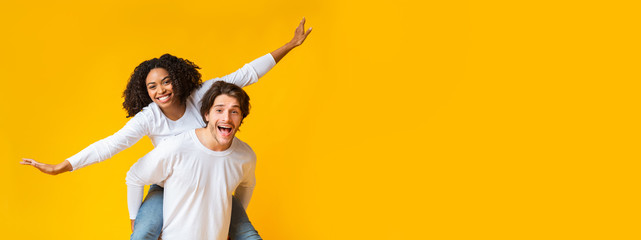 Carefree interracial couple fooling and having fun together over yellow background