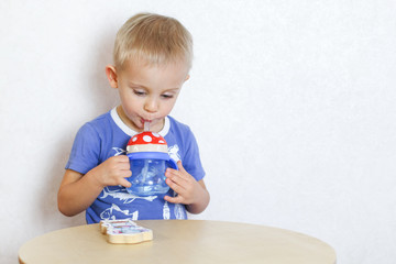 Blonde Toddler boy drinking water from a drinker with a straw