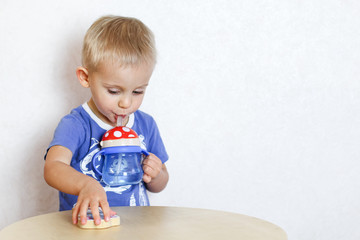 Blonde Toddler boy drinking water from a drinker with a straw