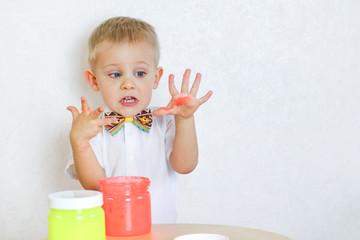 Toddler boy playing with slime and is not happy with his dirty slimy hands