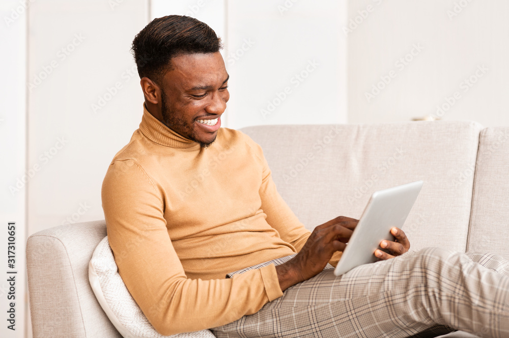 Poster Happy Guy Using Tablet Computer Sitting On Couch At Home