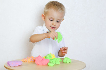 Toddler boy eagerly playing with kinetic plasticine, a great sensory activity to develop fine motor...