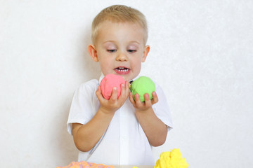 Cute blonde 2-year-old toddler boy playing with kinetic molding mass, it is a great activity to develop fine motor skills in kindergarten kids