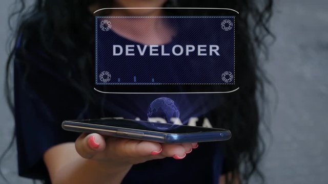 Unrecognizable curly brunette woman showing HUD hologram with text Developer. Girl uses technology of the future on a mobile screen