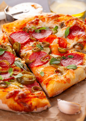 Homemade spicy pepperoni pizza and cooking ingredients. Pepperoni pizza on a gray wooden table.